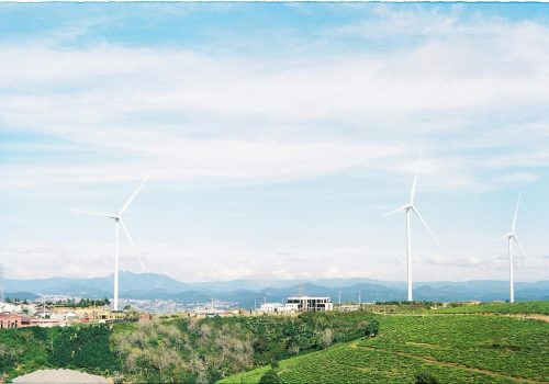 Aerial view of wind turbines set amidst the lush rural landscape of Dalat, Vietnam, showcasing renewable energy.
