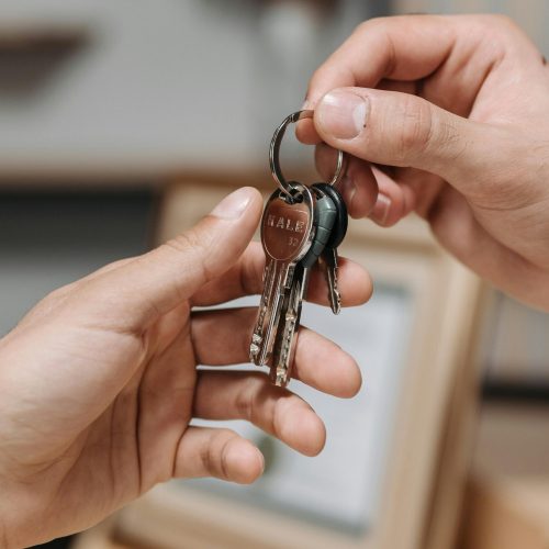 A close-up image of two hands exchanging a set of keys indoors.